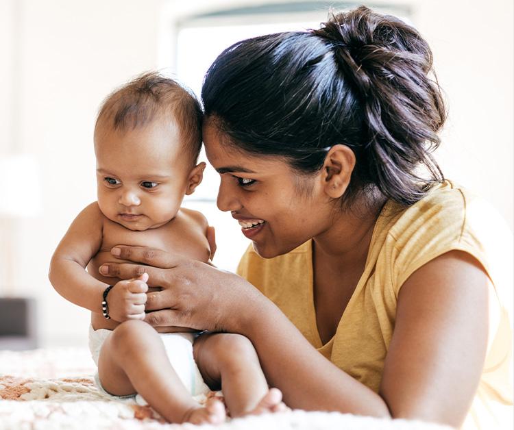 Mes sonriendo y sosteniendo a un bebé de 6 meses